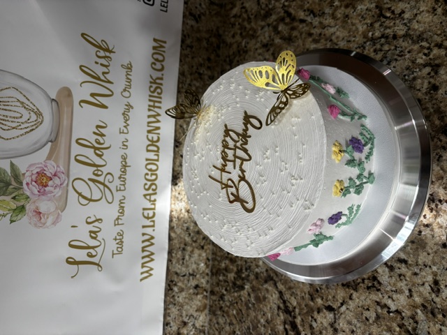 White birthday cake with gold butterflies and a floral border