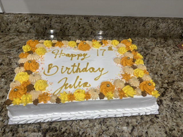 White cake bordered with orange and gold piped rosettes