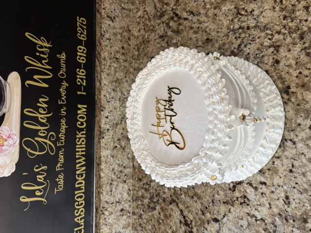 White ruffled cake with a bow and gold bead accents