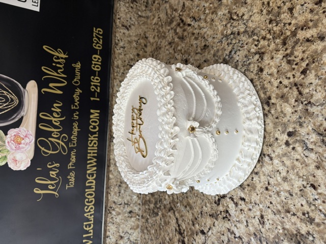 White cake with draped piping and gold bead strands